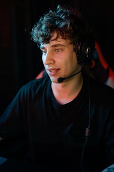 A focused young man with a headset engaged in gaming, immersed in the digital world.
